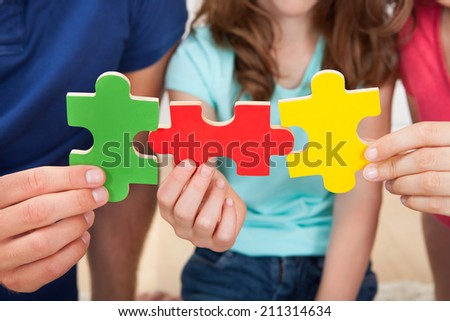 Midsection of family joining puzzle pieces at home
