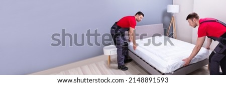 Two Male Professional Movers In Uniform Placing The Mattress Over The Bed In New House Stockfoto © 