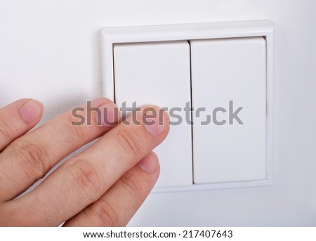 Close-up Of Hand Presses The Light Switch On The Wall