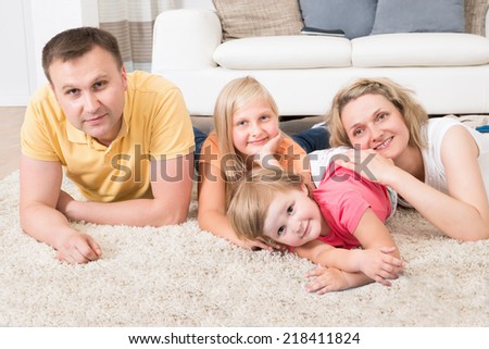 Happy Young Family Laying On Carpet At Home