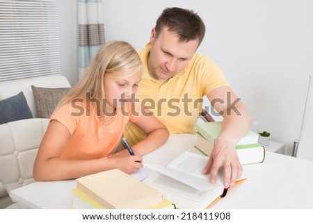 Father Helping Daughter With Homework At Home