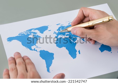 Cropped image of businessman marking places on world map at desk