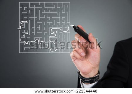 Cropped image of businessman solving maze puzzle on transparent screen over gray background