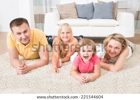 Happy Young Family Laying On Carpet At Home