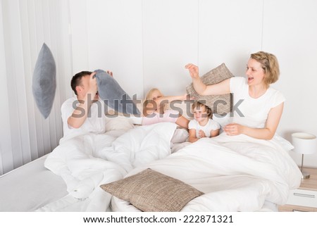 Family Having Pillow Fight In Bed At Home