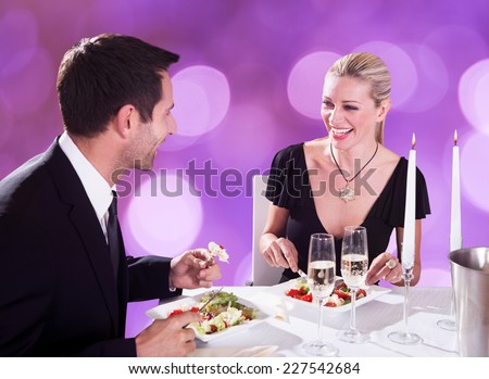 Happy young couple enjoying candlelight dinner at restaurant table