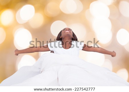 Happy young african woman stretching in bed