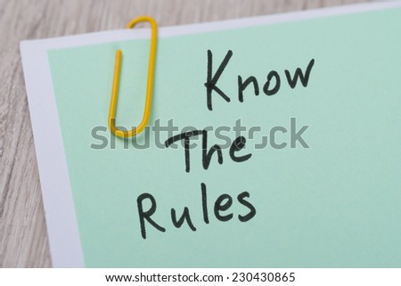 Closeup of Know The Rules ! written on green paper note with paperclip