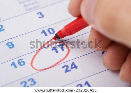 Cropped image of hand marking 17th date on calendar