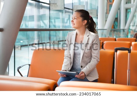 Young businesswoman with digital tablet waiting for flight at airport lobby