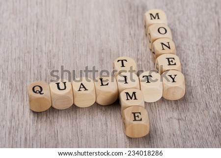 Closeup of Quality, Time and Money cubes arranged on wooden table