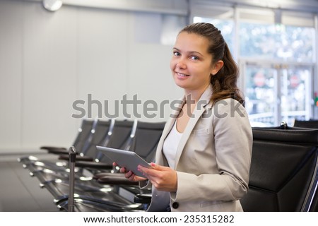 Portrait of young businesswoman using tablet computer while waiting for flight at airport lobby