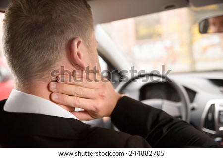 Rear View Of A Man Having Neck Pain While Driving A Car