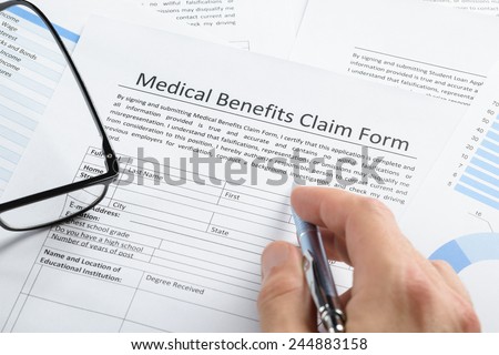 Close-up Of Hand Holding Pen Over Medical Claim Application Form
