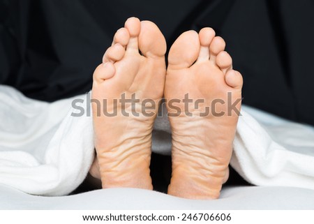 Close-up Of A Person\'s Feet Under The Blanket On Bed