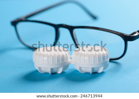 Close-up Of Eyeglasses In Front Of Lens Case On Blue Background