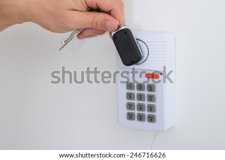 Close-up Of A Person Holding House Keys Arming A Security System
