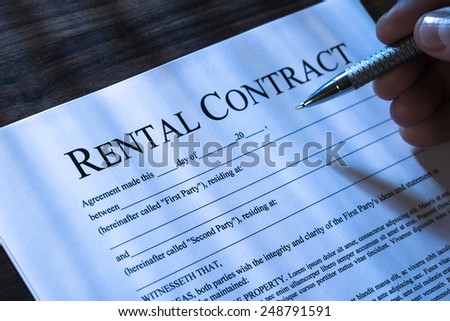 Close-up Of A Person  Filling Rental Agreement Form With Pen