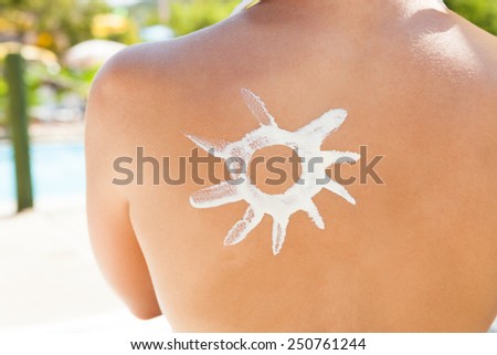 Midsection of young woman with sun shaped suntan lotion on back