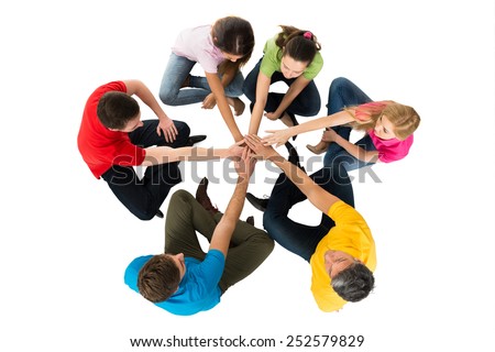 Group Of Friends Sitting In A Circle Stacking Hands Over White Background