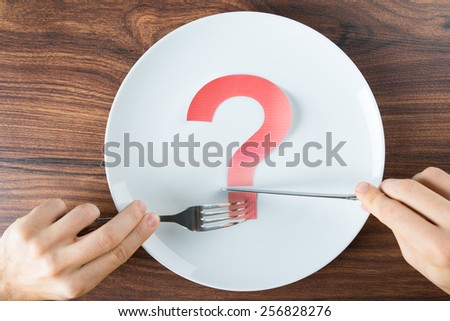 Close-up Of A Person With Red Question Mark On White Plate Holding Cutlery