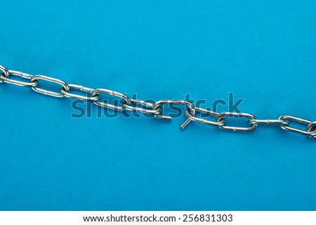 Close-up Of Broken Silver Chain Over Blue Background