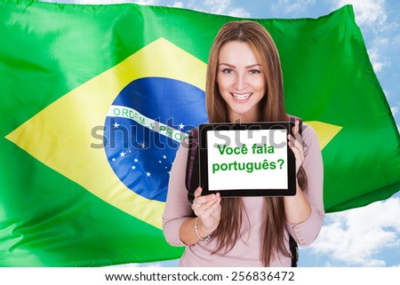 Young Woman Holding Digital Tablet Asking Do You Speak Portuguese In Front Of Brazilian Flag