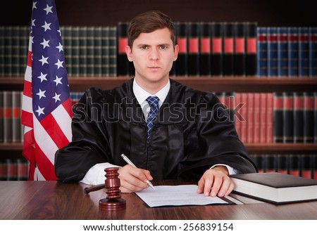 Portrait Of Young Male Judge Sitting In Courtroom