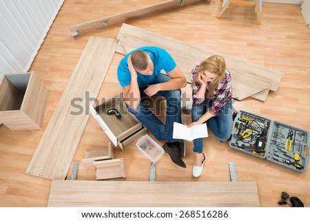 Portrait Of Thoughtful Couple With Disassembled Furniture Parts In New Home