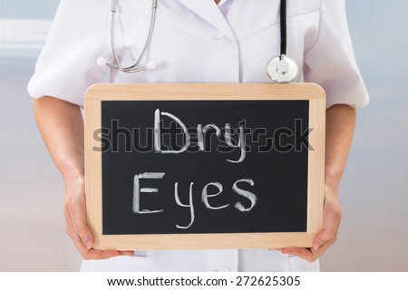 Female Doctor Holding Slate Chalkboard With The Text Dry Eyes