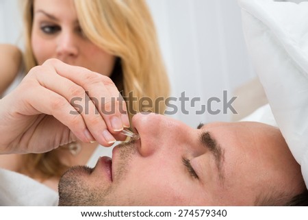 Close-up Of Woman Inserting Nose Clip Device Into Sleeping Man Nose