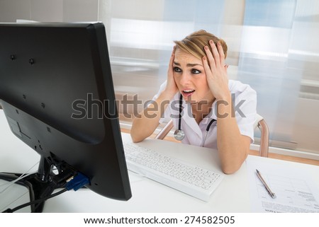 Young Female Worried Doctor Looking At Computer In Clinic