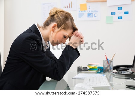 Portrait Of Upset Young Businesswoman Sitting At Desk In Office