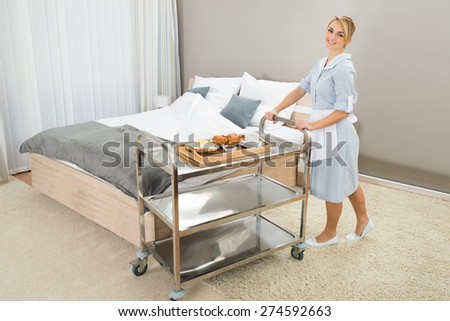 Young Happy Woman Pushing Trolley With Breakfast In Hotel Room