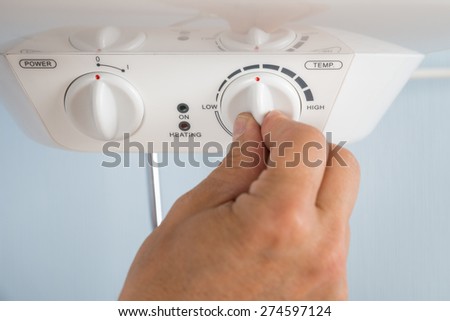 Close-up Of A Person\'s Hand Adjusting Temperature Of Electric Boiler