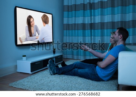 Couple With Remote Control Watching Movie At Home