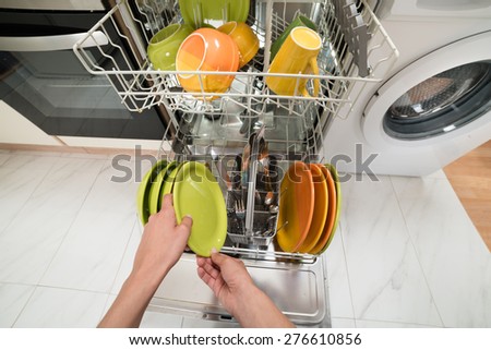 High Angle View Of Person Hands Putting Plate In Dish Rack