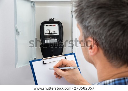 Technician Writing Reading Of Meter On Clipboard