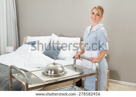 Young Beautiful Maid With Trolley In Hotel Room