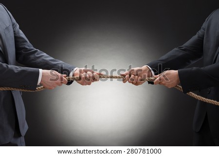 Close-up Of A Two Businessman Pulling Rope In Opposite Direction
