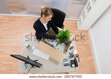 High Angle View Of Businesswoman Packing Belongings In Cardboard Box