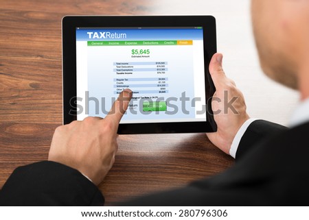 Close-up Of A Businessman Filling Tax Return Form On Digital Tablet