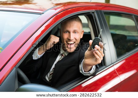Excited Businessman Sitting In A Car Showing New Car Key