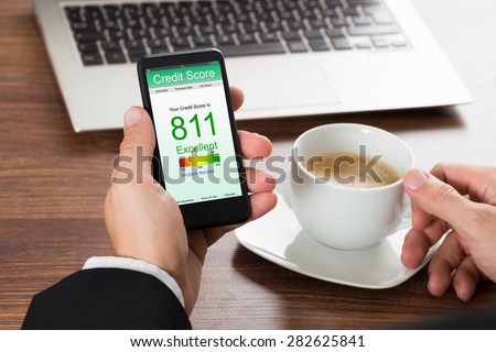 Close-up Of A Businessman Checking Credit Score Online On Cellphone While Having Coffee