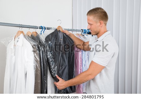 Young Man Getting Coat In Dry Cleaning Store