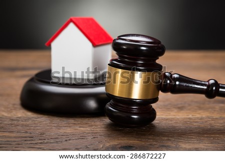 Close-up Of House Model With Gavel On Wooden Table