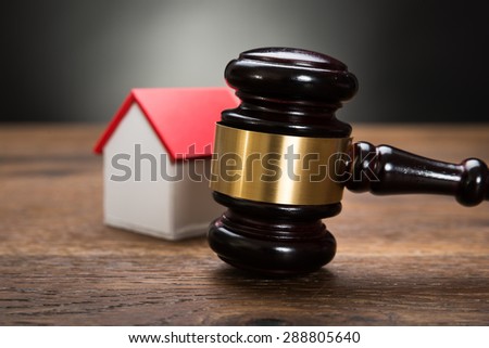 Close-up Of House Model With Gavel On Wooden Table