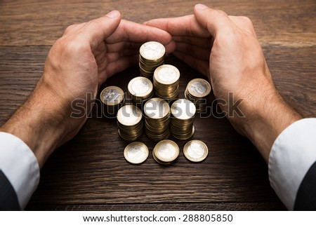 Close-up Of A Businessman\'s Hand Protecting Stack Of Euro Coins