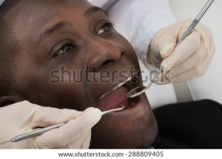 Close-up Of Doctor Hands Doing Dental Check Up Of Male African Patient