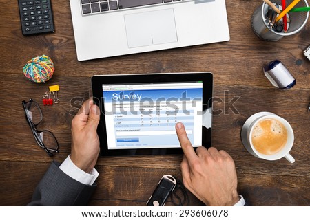 Close-up Of A Businessman Filling Online Survey Form On Digital Tablet